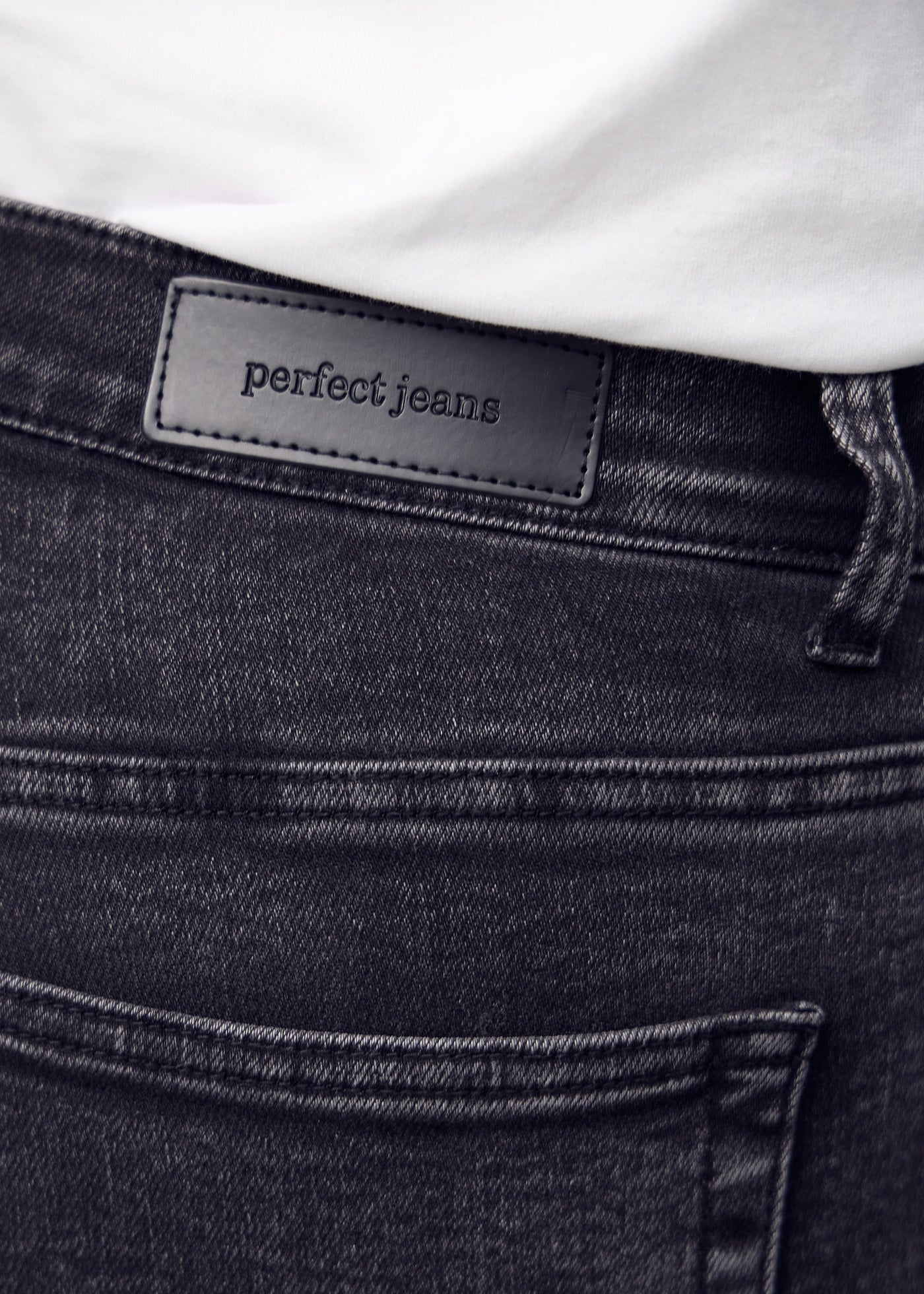Baglommen på de mørkegrå denim – detaljebillede med fokus på logo og denimtekstur.