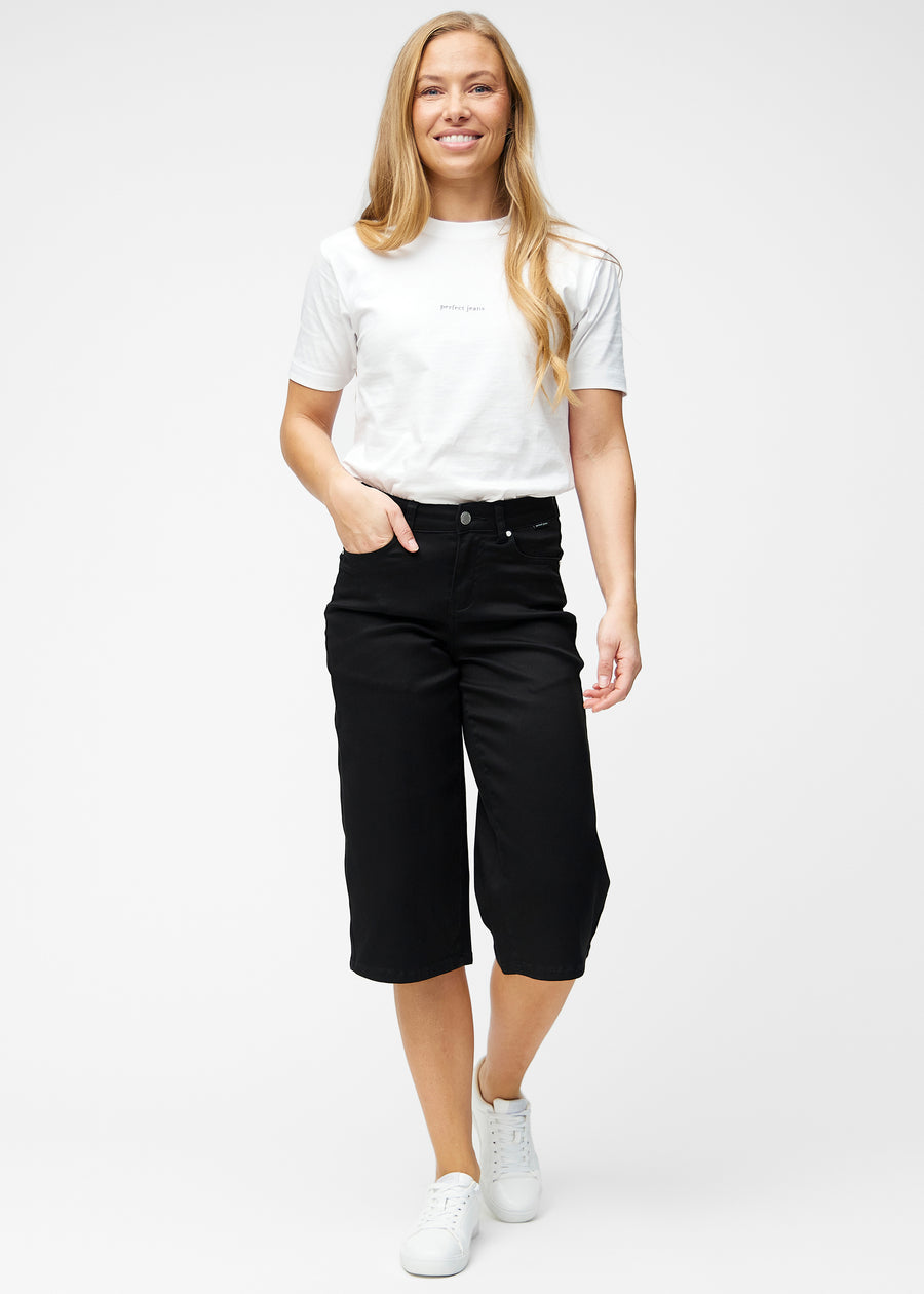 Model viser løse, sorte capris i farven Ravens i bevægelse og demonstrerer pasform og materiale.