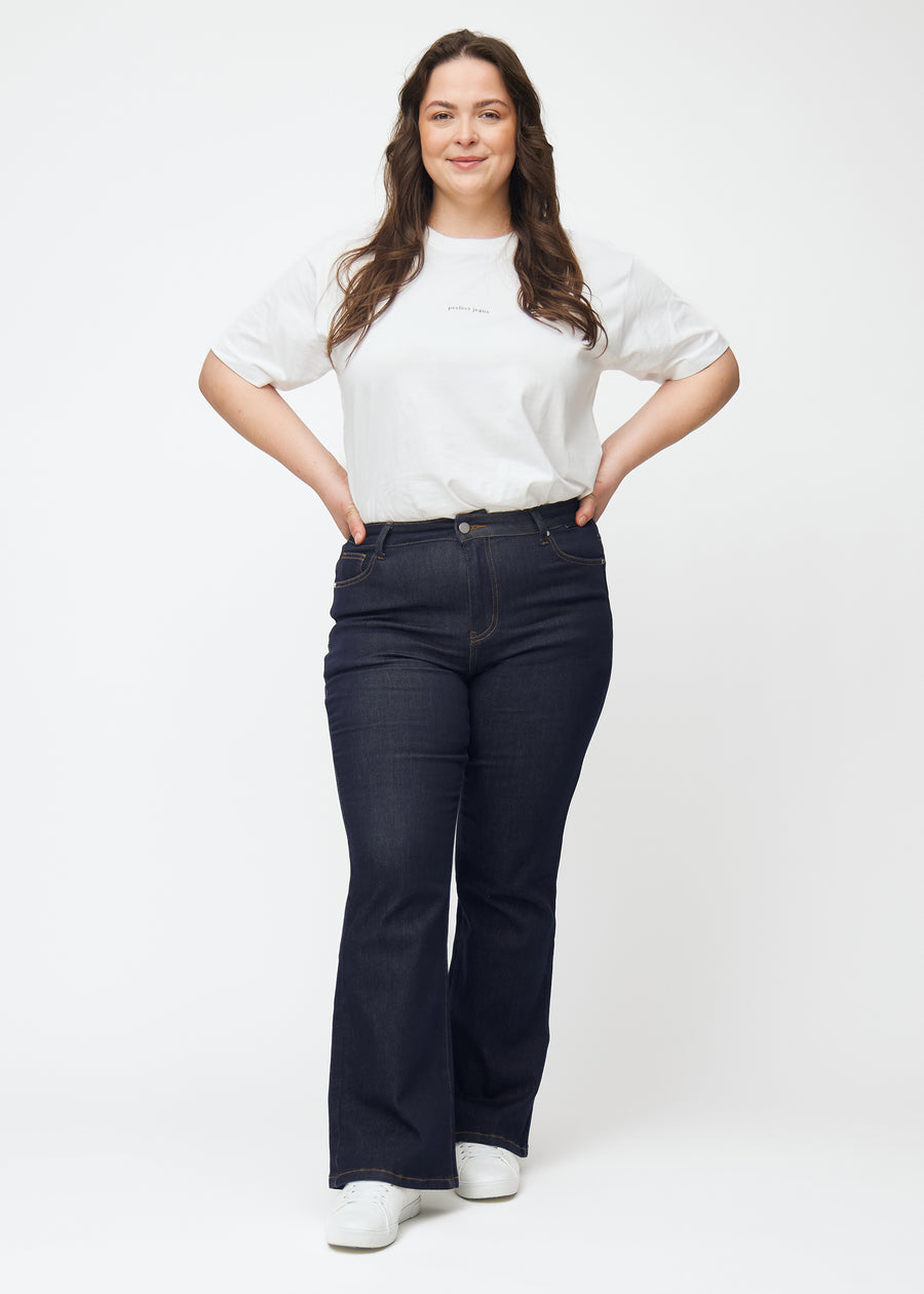 Plus-size model viser dyb mørkeblå denim jeans til kvinder i farven Midnights med bootcut pasform i bevægelse.