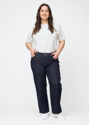 Plus-size model viser dyb mørkeblå denim jeans til kvinder i farven Midnights med loose pasform i bevægelse.