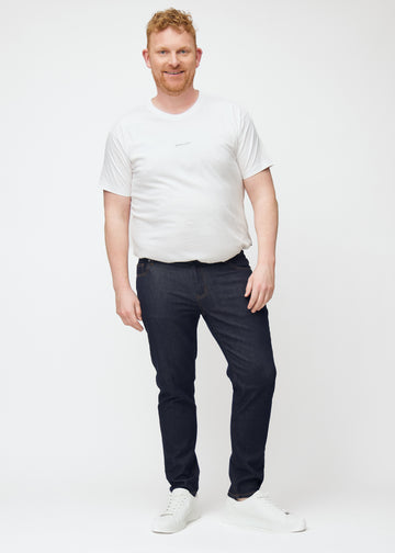 Plus-size model viser dyb mørkeblå denim jeans til mænd i farven Midnights med slim pasform i bevægelse.