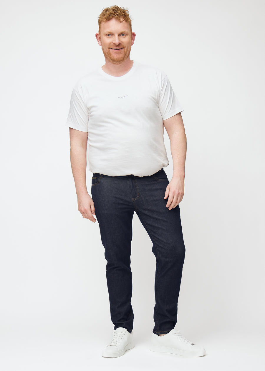 Plus-size model viser dyb mørkeblå denim jeans til mænd i farven Midnights med slim pasform i bevægelse.